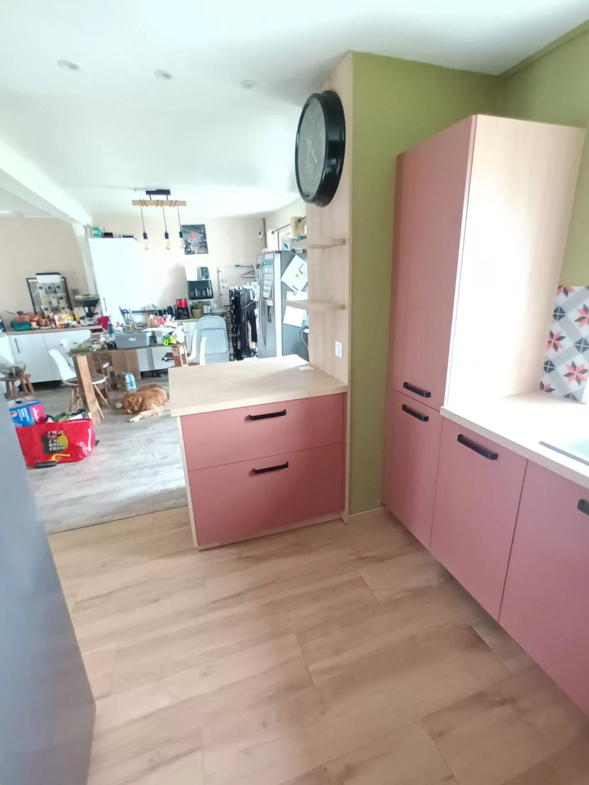 Vue depuis l'espace de vie sur l'îlot central et les tablettes murales décoratives en décor chêne naturel.