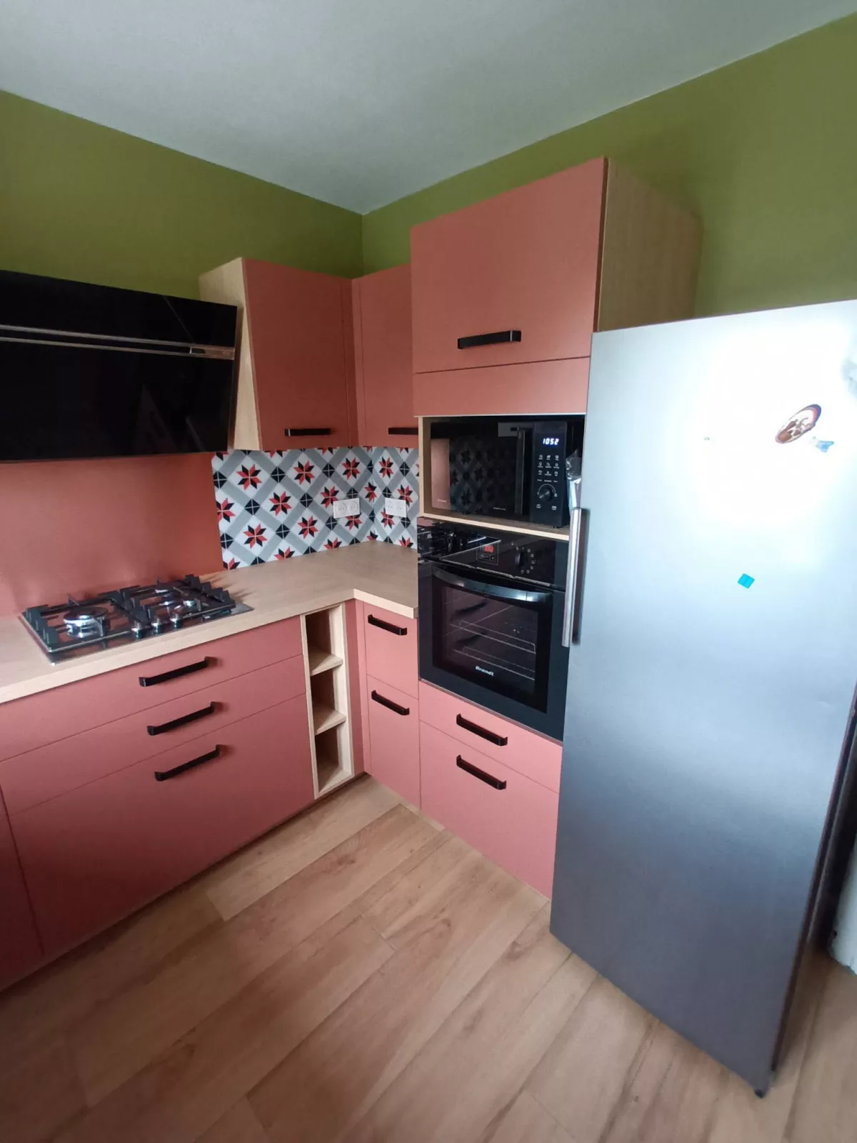 Gros plan sur la zone de cuisson équipée d'un four encastré et d'une hotte inclinée noire.