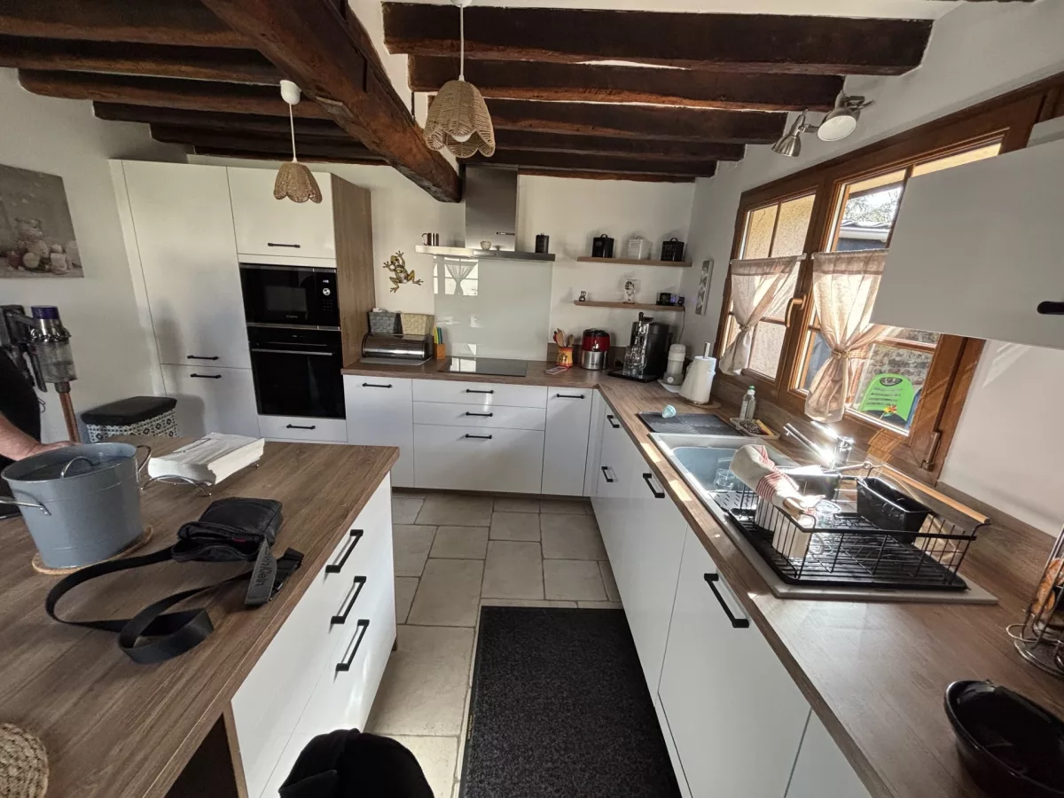Vue rapprochée de l'espace de cuisson, de la crédence et du linéaire de meubles bas blancs avec poignées noires.