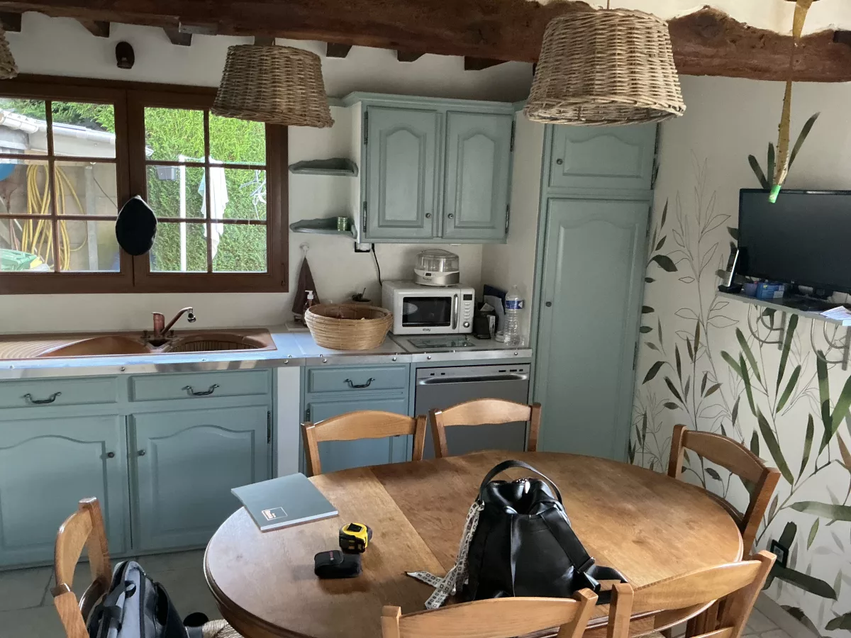 Ancien coin repas avec une table ronde en bois, des chaises traditionnelles et des meubles hauts de l'ancienne implantation.
