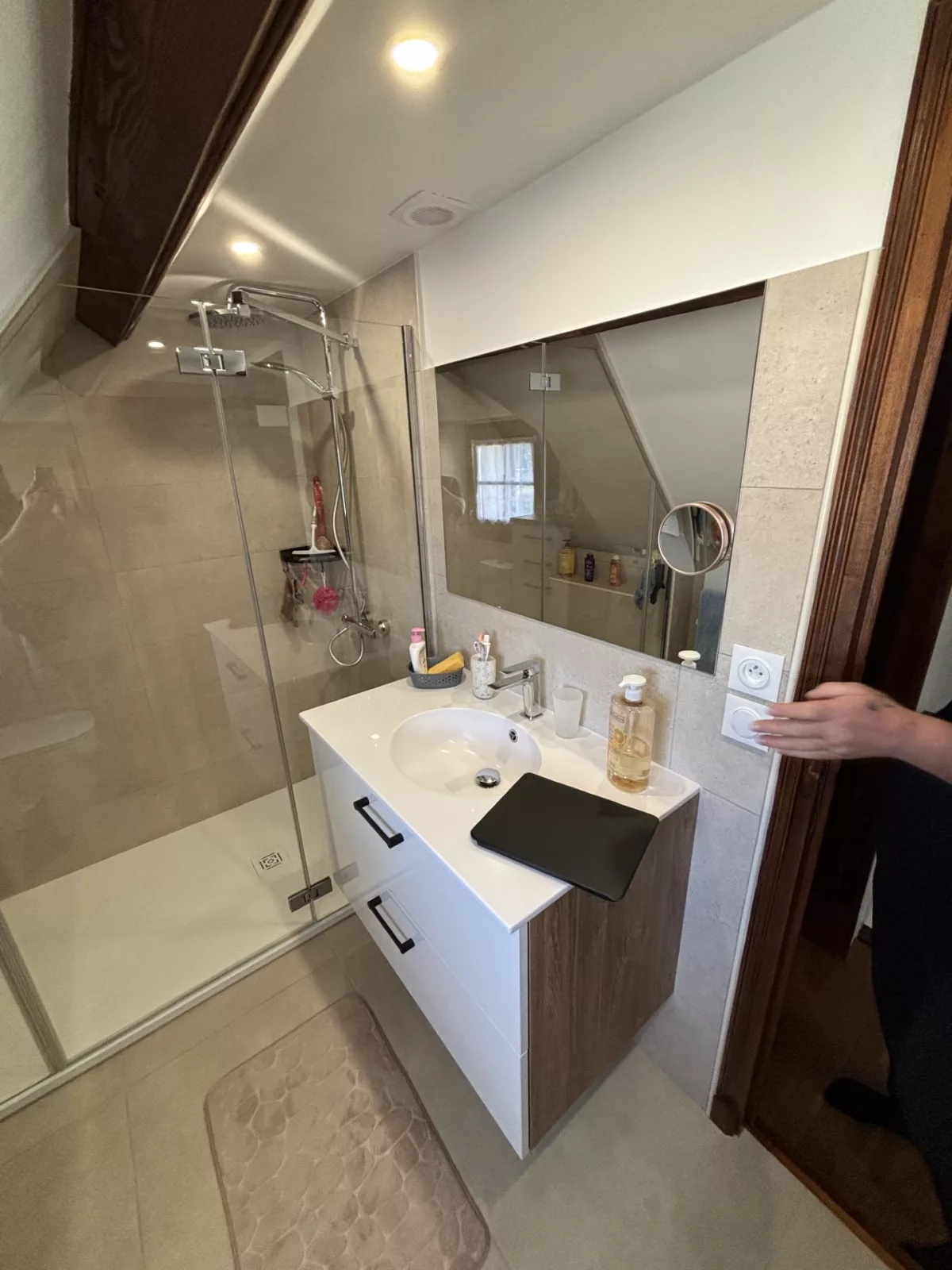 Vue latérale du meuble vasque et du miroir mural avec éclairage encastré au plafond dans l'espace douche.